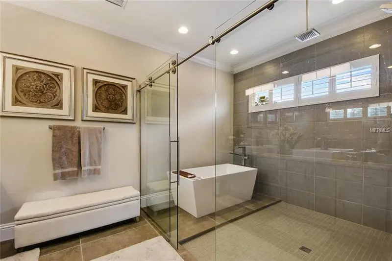 A bathroom with a tub, shower and bench.